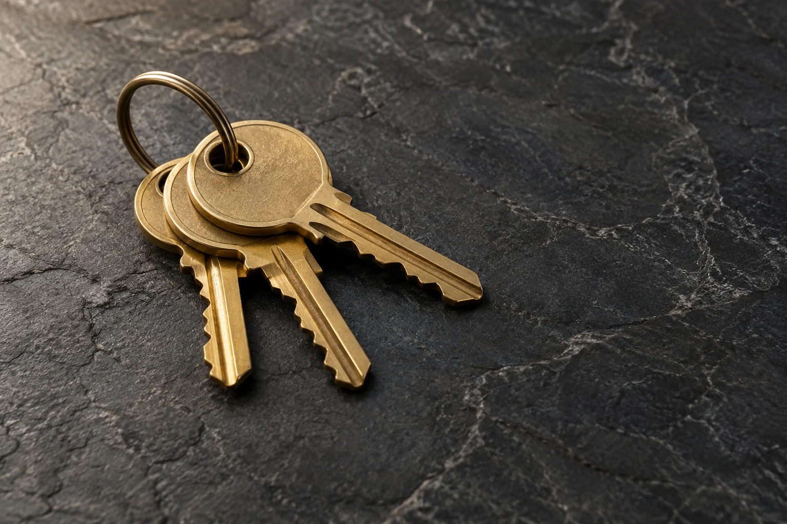 Brass house keys resting on charcoal stone